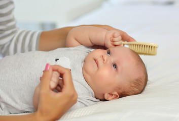 Mom combs a newborn baby with a special hair brush