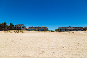 Panoramic view of a beautiful beach with apartments buildings at the background. The sky is clear and intense blue.