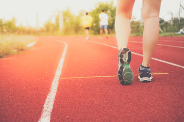 Woman wear sport shoe on to run in running court background.
