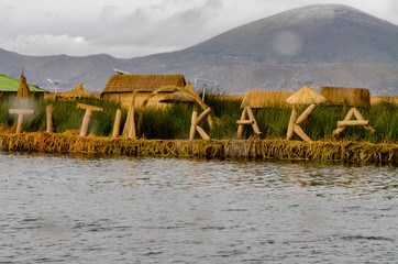 Titikaka sign made of totora by the Uros in a floating Island with a mountain on the back