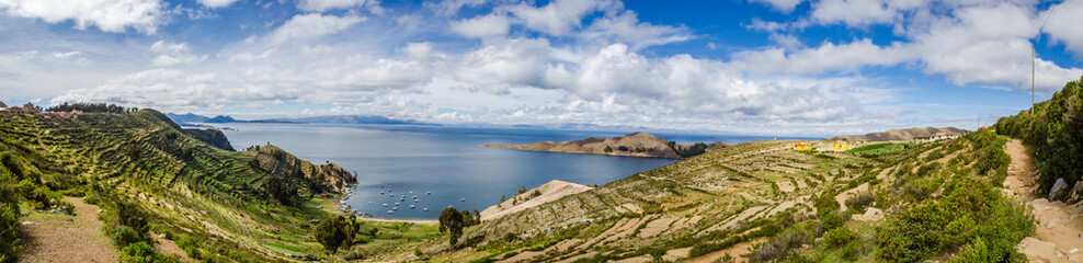 Panoramic on Isla del Sol with plantations, road, boats and Titikaka Lake on a sunny day