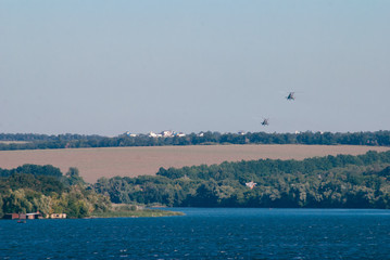 A pair of combat helicopters flying over the river