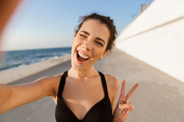 Cheerful young sportswoman standing outdoors