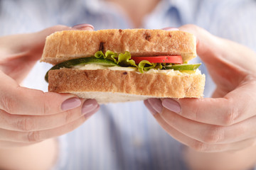 Woman eats a big sandwich with meat and wegetables