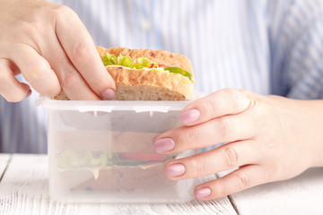 Woman eating a breakfast sandwich and drinking coffee while working