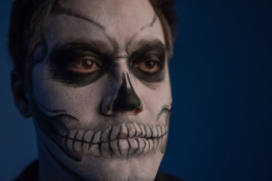 Portrait of a young man with a skull makeup for Halloween on a black background