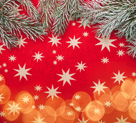 Red xmas background with stars. Fir branches and light blips. Top view, Text space.