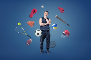 A thoughtful muscular man stands surrounded by different sport gear flying around him.