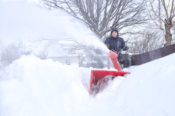 young man removes snow with a snowplower