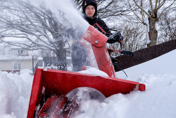 young man removes snow with a snowplower