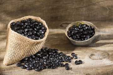 Fototapeta na wymiar Raw black beans on the wooden background