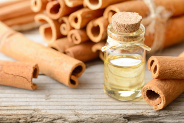 cinnamon essential oil in the glass bottle, with cinnamon sticks, on the wooden board
