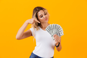 Photo of gorgeous woman in basic clothing holding fan of dollar money, isolated over yellow background