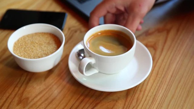 Close-up of man's hand pours sugar into a cup of coffee at the bar, and stir it
