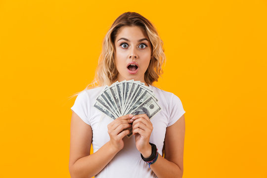 Photo of shopper woman in basic clothing holding fan of dollar money, isolated over yellow background