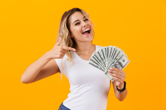 Photo of rich woman in basic clothing holding fan of dollar money, isolated over yellow background