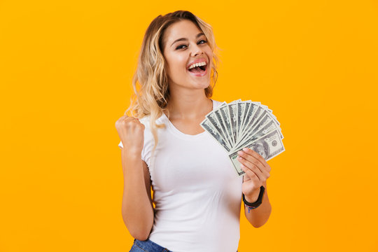 Photo of charming woman in basic clothing holding fan of dollar money, isolated over yellow background