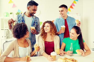 Fototapeta premium corporate, celebration and people concept - happy friends or team eating sandwiches with coffee and non-alcoholic drinks at office party