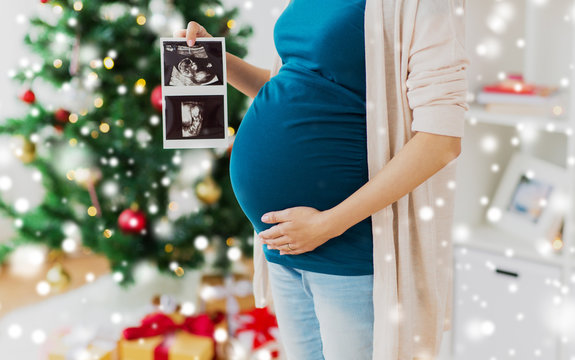 pregnancy, winter holidays and people concept - close up of pregnant woman with baby ultrasound images at christmas
