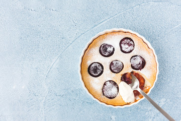 Homemade Clafoutis with Plums on Blue Concrete