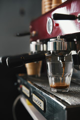 close-up view of professional coffee maker and glass cup with espresso