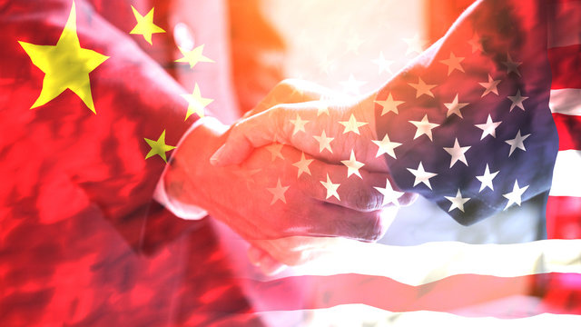 Businessman shake hand over United States of America and China flag.