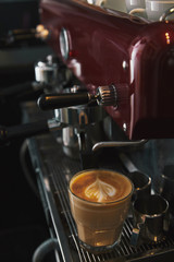 close-up view of coffee machine and glass cup with cappuccino