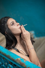 A young girl smokes a thin cigarette.