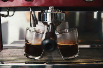close-up view of two glasses and coffee machine preparing espresso