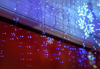 New Year's garland on the storefront. New Year's shopping and gifts. New Year background. Multicolored Christmas lights on the supermarket showcase. New Year discounts - concept. Red glass showcase.