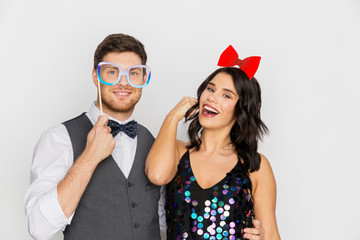 celebration, fun and holidays concept - happy couple posing with party props