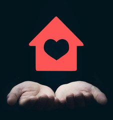 Hands holding red house with heart.