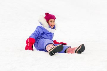 childhood, leisure and season concept - happy little girl in winter clothes outdoors