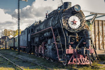 Vintage black steam locomotive train with wagons on station.