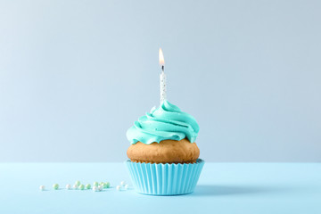 Delicious birthday cupcake with candle on light background