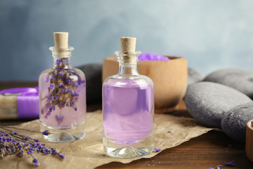 Bottles with natural herbal oil and lavender flowers on table against blurred background