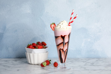 Glass of delicious milk shake and bowl with strawberries on table