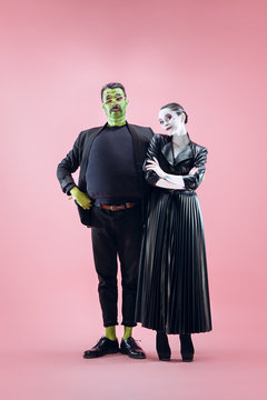 Halloween Family. Happy Couple In Halloween Costume And Makeup. Bloody Theme: The Crazy Maniak Faces On Pink Studio Background