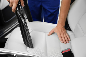 Man using vacuum cleaner in auto, closeup. Car wash
