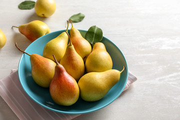 Plate with ripe pears on light table. Space for text