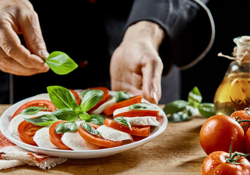 Hands of a chef preparing a Caprese salad