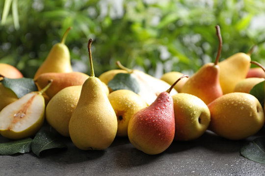 Ripe pears on grey table against blurred background