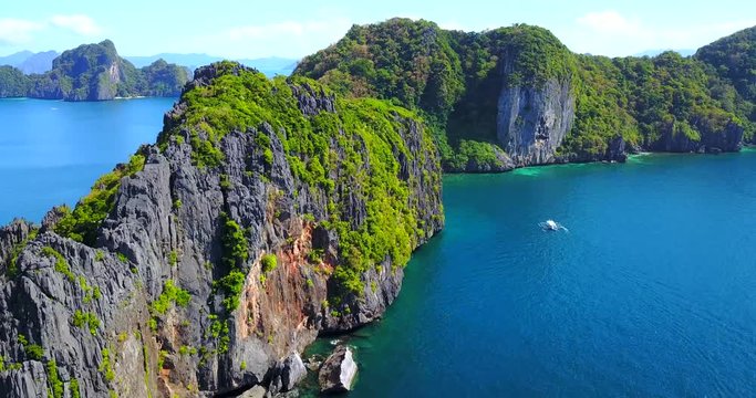 Overhead Approaching View Of Dramatic Rock Cliffs Overlooking Catamaran Boat In Tropical Lagoon Archipelago - El Nido, Palawan, Philippines