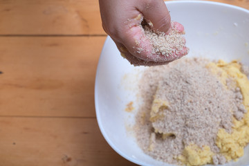 Close up of female hands making hazelnut cookies from sliced almonds and flour with coffee powder .