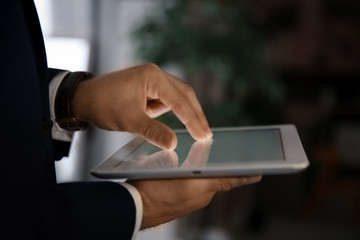 Businessman using digital tablet at workplace, closeup of hand. Mockup for design