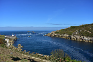 Torre de Hercules public park with walking area. Bay with cliff, rocks and blue sea with foam. Sunny day, La Coruña, Spain.