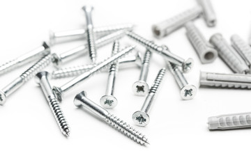 Tornillos clavos y tacos de plástico sobre fondo blanco