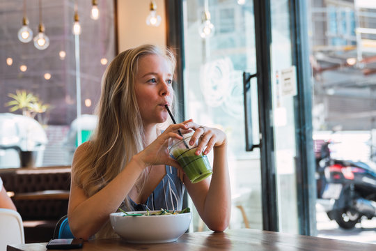 Woman Having Drink And Meal In Cafe