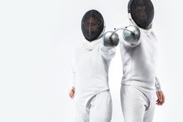 Two Young fencers athletes wearing mask and white fencing costume and holding the sword. Isolated...