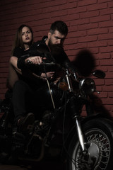 Fototapeta na wymiar Bearded man and sensual woman ride motorbike, adventure concept. Lets go on a new adventure